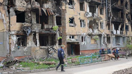 Un bărbat trece pe lângă un bloc de apartamente distrus din Mariupol.
