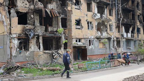 A man walks past a destroyed apartment building in Mariupol.