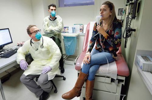 Yale pulmonary and critical care physician Dr. Jon Koff, left, and Yale University researcher Benjamin Chan, center, watch as Ella Balasa, 26,inhales a bacteriophage.