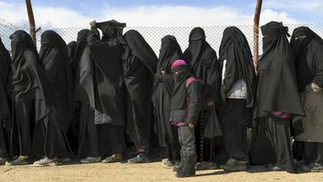 Foreign IS wives and children line up at a camp in Syria to be taken to shops in 2019.