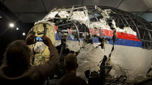 People take photos of the reassembled fuselage of MH17. (AAP)