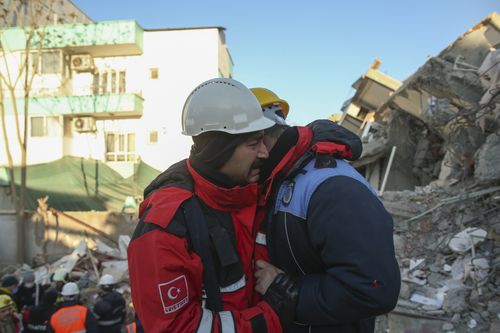 Rescuers weep by a collapsed building in Adiyaman, southern Turkey, Thursday, Feb. 9, 2023. 