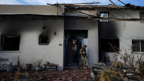 Un soldat israélien inspecte une maison endommagée par des militants du Hamas dans le kibboutz Beeri, en Israël, le mardi 17 octobre 2023.