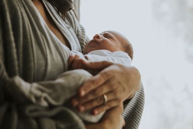 Mother holding her baby indoors