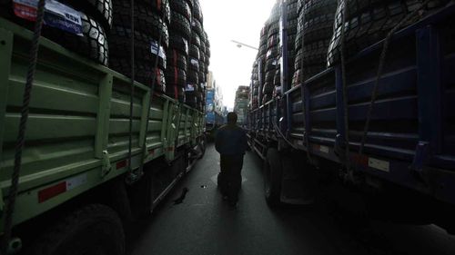 A Chinese truck driver who drives goods to North Korea walks between full-loaded trucks in Dandong. (AAP)