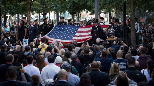 Firefighters hold up a flag at in New York City. (AFP)