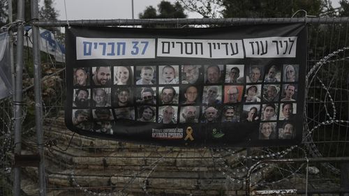 A poster shows portraits of Bibas family, top row from second left: Yarden, Shiri, and their sons Ariel and Kfir, who were kidnapped to Gaza on Oct. 7, 2023, in Jerusalem, Friday, Feb. 21, 2025. Letters on top read, "37 members of Kibbutz Nir Oz are still missing". (AP Photo/Mahmoud Illean)