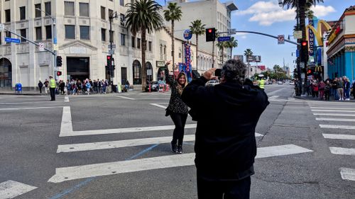 A tourist poses for a photo on Hollywood Boulevard. (9NEWS/Ehsan Knopf)