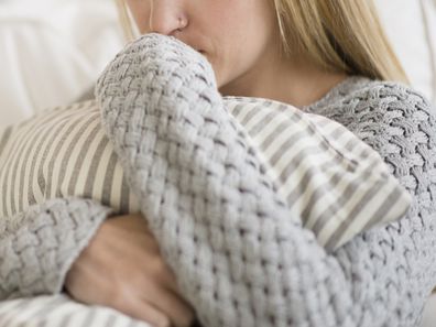 Woman who has suffered a stillbirth hugging pillow