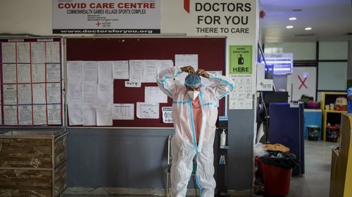 A paramedic prepares for duty at a makeshift COVID-19 care center at an indoor sports stadium, in New Delhi, India, 