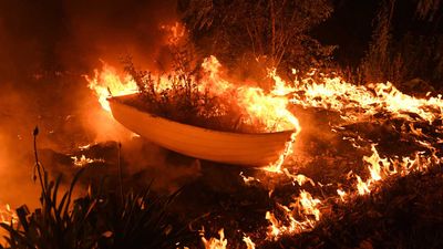 A bushfire spreads over a boat.