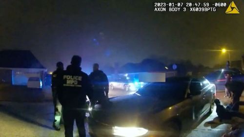 In this still from video released by the City of Memphis, Memphis Police officers stand around as Tyre Nichols leans up against a car after being detained and beaten.