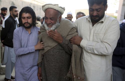 People mourn over the death of their relative, a  police officer killed in the Monday's suicide bombing inside a mosque, in Peshawar, Pakistan.