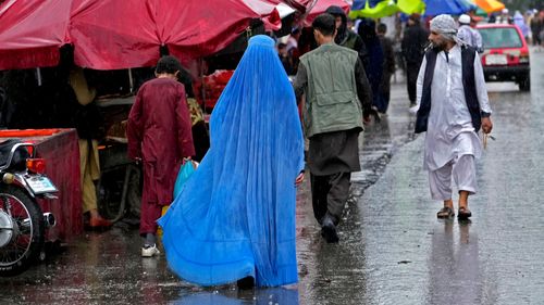 一名阿富汗妇女在阿富汗喀布尔市中心的旧市场上行走。