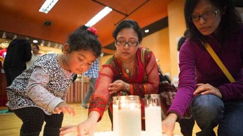 Support has flowed in from around the world. Here, toddler Samataa Shrestha helps her mother Pragya place a small candle onto a plate with friend Beenu Maharjan during a community gathering and prayer organised by the Nepal Seattle Society in Washington state. (AP/Seattle Times)