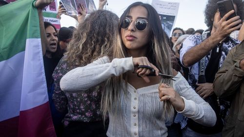 A woman cuts her hair during a protest against the death of Iranian Mahsa Amini and the government of Iran in Istanbul, Turkey.  