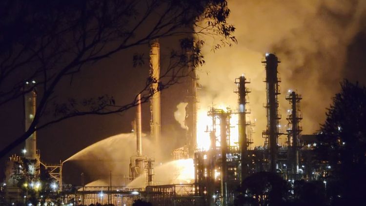 Petrol prices fall despite refinery fire, but treasurer warns Australians could face economic pain
