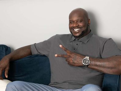Shaquille O'Neal sitting on a couch holding up a peace sign