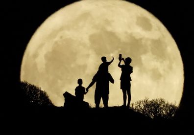 A family stand with the full moon known as the "Sturgeon Moon"