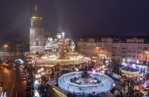 Des foules de gens célèbrent le Nouvel An sur la place Sophia avec un arbre de Noël illuminé et le marché des fêtes avec la cathédrale Sainte-Sophie en arrière-plan, à Kyiv, Ukraine, le 31 décembre 2021 