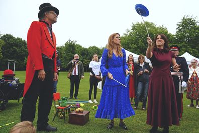 Princess Beatrice, centre, and Princess Eugenie attempt to spin plates during the Big Jubilee Lunch organized by Westminster Council