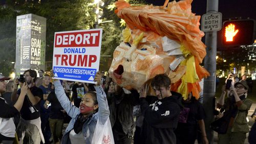 Protesters carry a paper head of President-elect Donald Trump during a protest in front of City Hall, Los Angeles. (AAP)