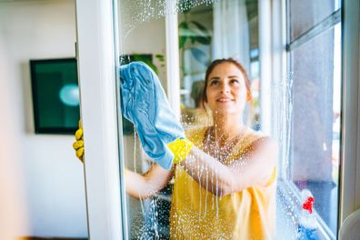 Young woman washing window 