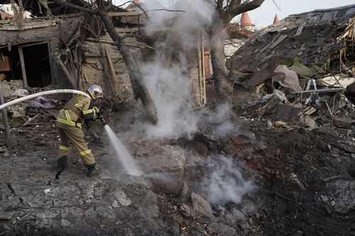 Firefighters extinguish a fire next to houses destroyed during a Russian attack in Kyiv, Ukraine, Saturday, Dec. 31, 2022. 