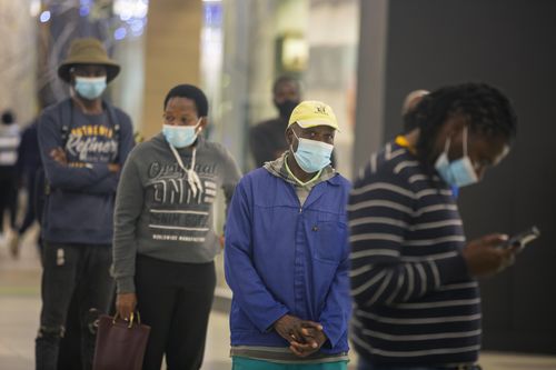 People lineup to get cash at a bank in a shopping mall in Johannesburg, South Africa, Friday Nov. 26, 2021. 