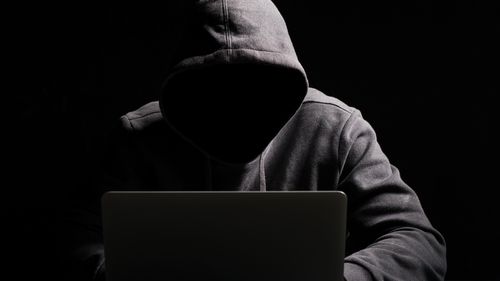 Hacker scammer dark hooded laptop computer