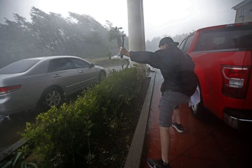 A storm chaser films from underneath a hotel canopy during Hurricane Michael in Panama City Beach