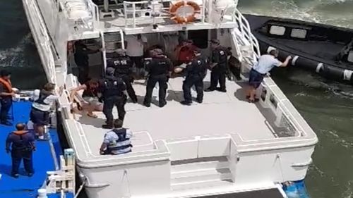 Six men and a woman were removed from the ship and onto an awaiting boat at Bradleys Head this afternoon. (9NEWS)