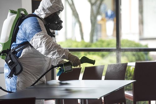 Service technician Hazel Maldonado of Guardian Touchless Solutions wears a protective suit as he uses an electrostatic gun to clean Villaggio del Vino in Tyler, Texas.