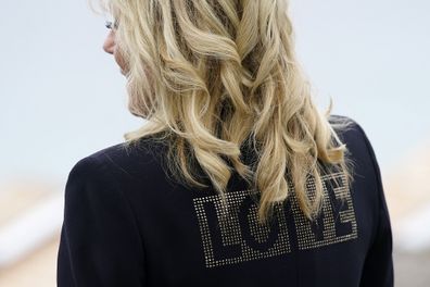 First lady Jill Biden turns around to show the word "love" on the back of her jacket as she speaks with reporters after visiting with Carrie Johnson, wife of British Prime Minister Boris Johnson.