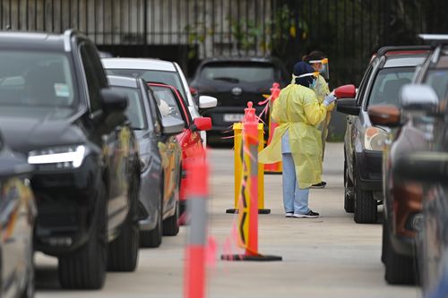 Medical officers attend to cars lining up at a drive-through COVID-19 testing clinic at Auburn in NSW. 1st Jan 2021. Photo: Steven Saphore / SMH