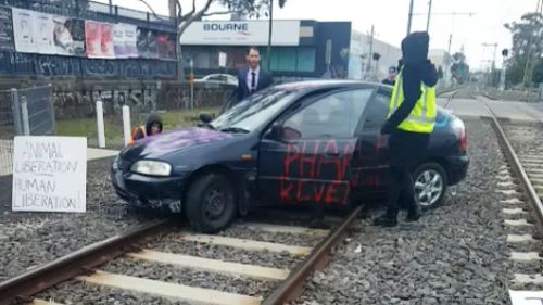 Protestors drove a car onto train tracks near Flemington. (AAP)