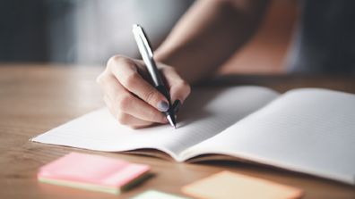 Woman writing in an exercise book using a pen