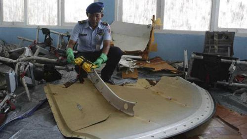 An Indonesian air force soldier holds pieces from AirAsia Flight 8501 at Disaster Victim Identification room at Pangkalan Bun. (AP)