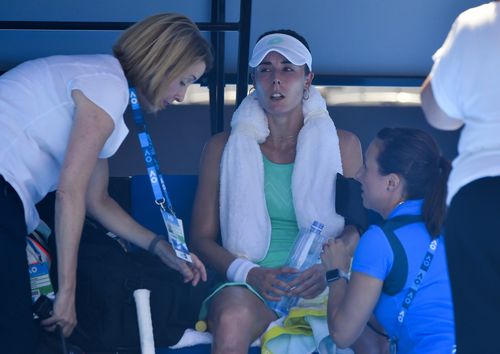 France's Alize Cornet is attended to by a trainer and tournament staff after suffering from the heat during her third round match against Belgium's Elise Mertens at the Australian Open tennis championships. (AAP)
