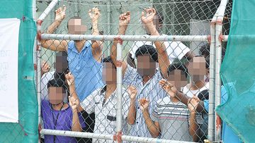 A March 21, 2014 file image of Asylum seekers staring at media from behind a fence at the Manus Island detention centre, Papua New Guinea. (AFP)