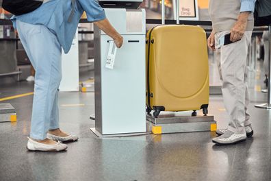 Cropped photo of a female tourist and her husband printing a luggage tag before the flight