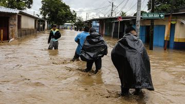 People wade trough a flooded street in Honduras on November 18, 2020, following the passage of Hurricane Iota.