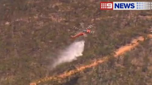 A helicopter waterbombs a fire at Sampsons Flat, in South Australia's Mount Lofty ranges in January. (9NEWS)