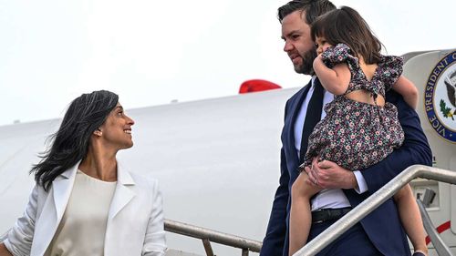 Second Lady Usha Vance looks back at Vice President JD Vance, carrying their daughter Mirabel as they disembark Air Force Two.