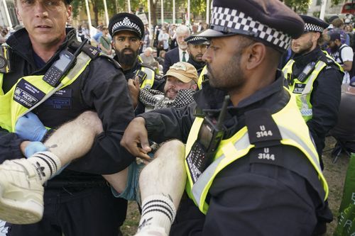 Policiais para manter o manifestante protestando em Aid Palestine People na Praça do Parlamento em Londres
