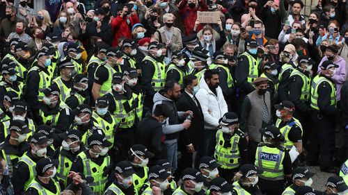 Two men stand surrounded by police and protesters, after being released from an Immigration Enforcement police van.