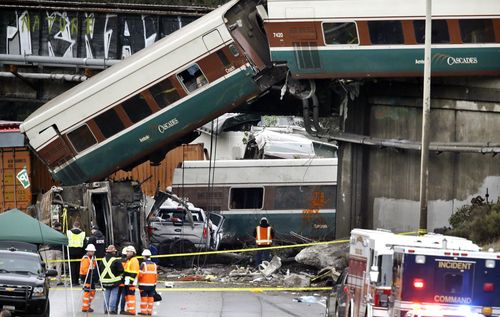 Cars from an Amtrak train that derailed above lay spilled onto Interstate 5 alongside smashed vehicles. (AAP)