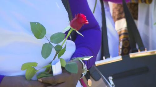 A woman holds a single rose in Mr Gony's honour.