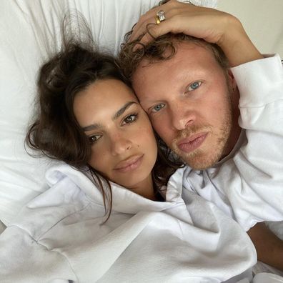 Emily Ratajowski and her husband Sebastian Bear-McClard lying in bed.