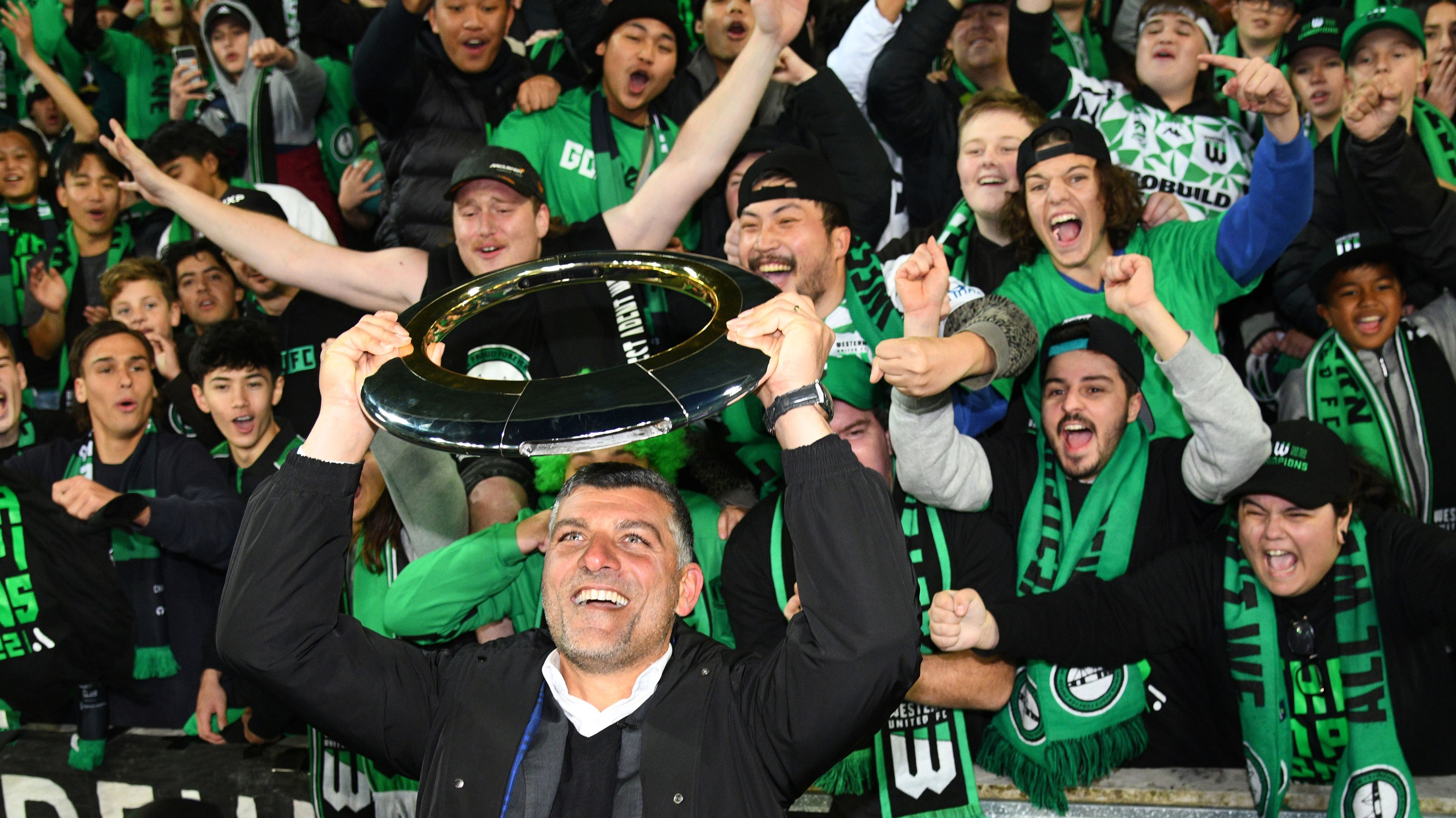 Western United coach John Aloisi lifts the trophy in front of supporters after winning the A-League Men&#x27;s grand final against Melbourne City in May 2022.